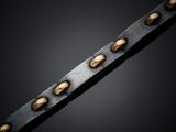 a close up of a metal chain with gold rivets on a black background