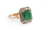 gros plan d'une bague avec une pierre verte entourée de diamants