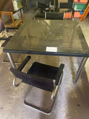 une table en verre avec une chaise noire au milieu