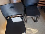 four black chairs in the corner of a room