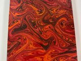 a red and black marbled notebook sitting on top of a white table