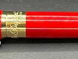 a red pen with gold trim sitting on a table