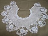 un col en dentelle blanche au crochet orné de fleurs, posé sur une table