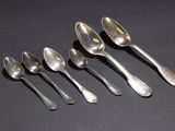 six silver spoons are lined up in a row on a black surface