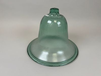 une cloche en verre vert posée sur une table blanche