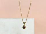 a gold necklace with a tear shaped ruby stone on a gold chain