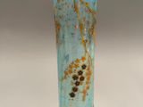 a blue glass vase with a branch of a plant on it