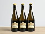 trois bouteilles de vin posées sur une table en bois