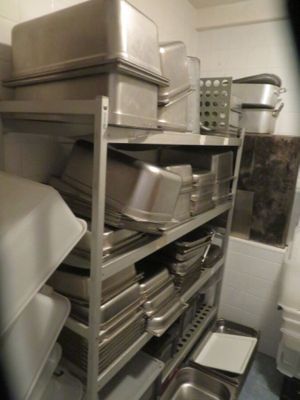 many pans and pans stacked on a shelf in a kitchen