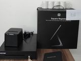 une boîte noire posée sur une table en bois, à côté d'un ordinateur portable et d'autres objets