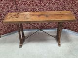 an old wooden table sitting in front of a wall with a red wallpaper