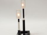 two black and white lamps on a white surface with one light turned on