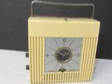 une petite horloge jaune posée sur une table blanche