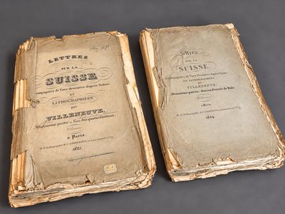 two old books sitting on top of a table next to each other