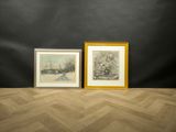 two framed paintings on a wooden floor in front of a black wall