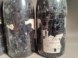 three bottles of wine are sitting on a table with peeling paint on them