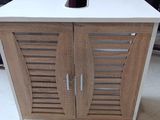 une armoire en bois à deux portes, sur laquelle est posé un verre à vin
