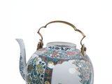 a tea pot with a handle that is decorated with flowers