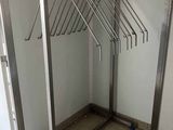 a rack with clothes hanging on it in the corner of a room
