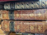 several old books are stacked on top of each other on a shelf