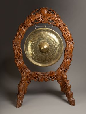 an image of a gong on a wooden stand against a gray background