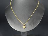 a gold necklace on a mannequin stand with a black background