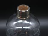 a glass vase with a gold lid on a black surface