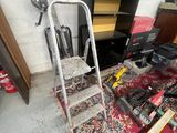 a ladder that is sitting on the floor next to a pile of tools