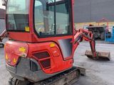 the back end of a small red excavator parked in a parking lot