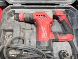 a red corded drill in a case with other tools in it