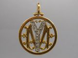 un gros plan sur un pendentif en or avec la lettre « m » au centre