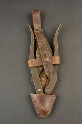 brown leather sheathed knife with two knives in it on a black surface