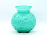 un vase vert posé sur une surface blanche