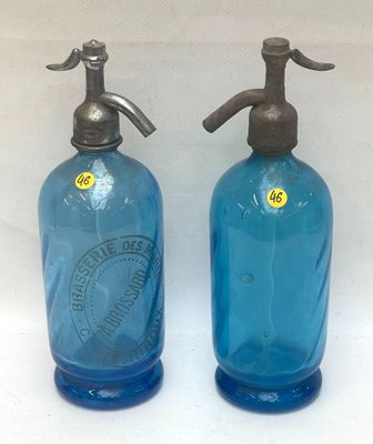 une paire de bouteilles en verre bleu surmontées de bouchons métalliques