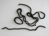 a close up of a black beaded necklace on a white surface