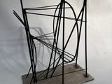 une sculpture métallique représentant un porte-revues posée sur une surface blanche