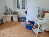 a room with a refrigerator, a desk, and a chair in it