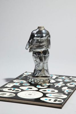 une figurine en argent posée sur un carrelage noir et blanc