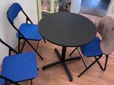 une table noire entourée de quatre chaises bleues