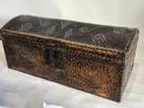 une boîte en bois ornée de rivets, posée sur une surface blanche