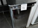 une poubelle sur laquelle est accrochée une pancarte, dans des toilettes