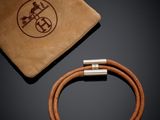 a brown leather bracelet and a brown sued bag on a black surface