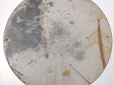 a round metal plate with rust on it on a white surface