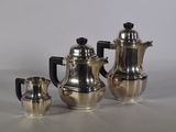 trois cafetières en argent et deux tasses en argent posées sur une table