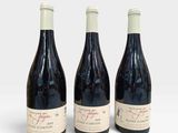 trois bouteilles de vin posées les unes à côté des autres sur une surface blanche