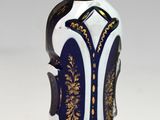 une bouteille en verre bleue et blanche surmontée d'une couronne