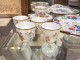 many cups and saucers sitting on a glass table