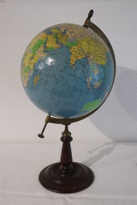 un petit globe bleu et jaune posé sur un socle en bois