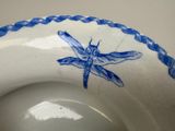 a blue and white bowl with a dragonfly painted on it