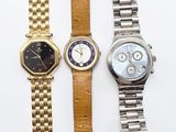 three watches are sitting on a white surface one is gold and the other is silver
